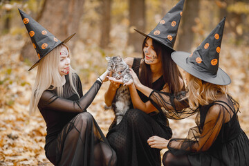 Three black witches in forest on Halloween