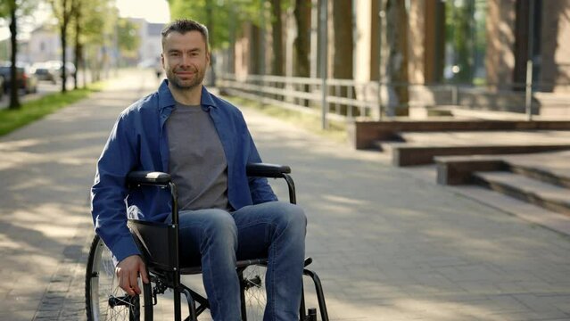 Portrait of the happy man on a wheelchair wearing casual clothes. A disabled smiled businessman riding in the middle of the day. People and disabled people concept