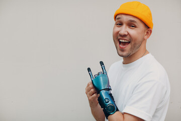 Young disabled man showing rock goat gesture with artificial prosthetic hand in casual clothes