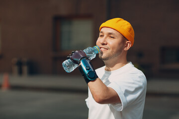 Young disabled man hold and drink bottled pure water with artificial prosthetic hand in casual...