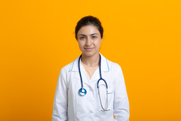 Portrait of indian doctor woman in white medical gown stethoscope isolated on yellow background. - Powered by Adobe