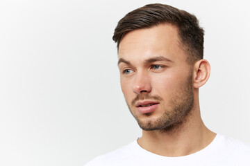 Fototapeta premium Closeup portrait. Flirted tanned handsome man in basic t-shirt raises eyebrow look aside posing isolated on white studio background. Copy space Banner Mockup. People emotions Lifestyle concept