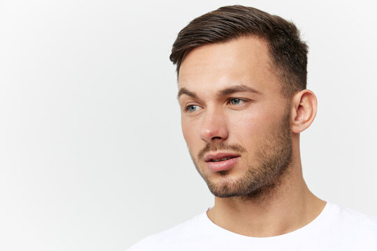 Closeup portrait. Flirted tanned handsome man in basic t-shirt raises eyebrow look aside posing isolated on white studio background. Copy space Banner Mockup. People emotions Lifestyle concept
