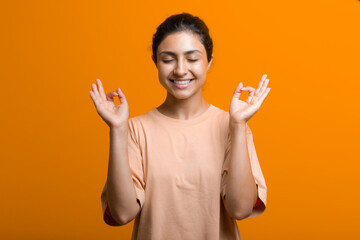 Portrait of young adult indian woman meditating zen like with ok sign mudra gesture.