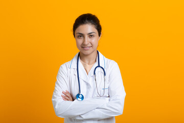 Portrait of indian doctor woman in white medical gown stethoscope isolated on yellow background.