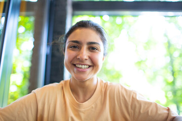 Headshot of indian woman sit on potdoor cafe waving hand looks to camera make video call chat use computer laptop webcam view, vlogger record webinar, job interview distantly concept.