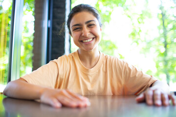 Headshot of indian woman sit on potdoor cafe waving hand looks to camera make video call chat use computer laptop webcam view, vlogger record webinar, job interview distantly concept.