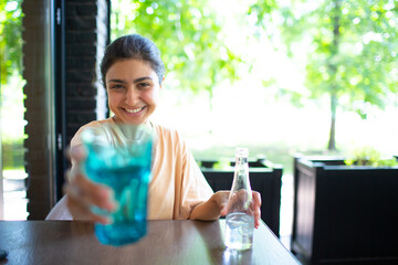 Indian woman drinking bottled still water at outside cafe. - Powered by Adobe