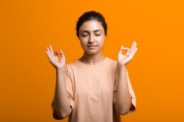 Portrait of young adult indian woman meditating zen like with ok sign mudra gesture.