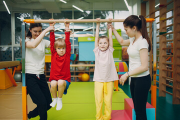 Kids doing pull up exercises in gym at kindergarten or elementary school. Children sport and...