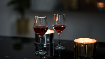 two glasses of red wine on a black table. Candle in the background