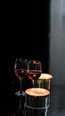 two glasses of red wine on a black table. Candle in the background