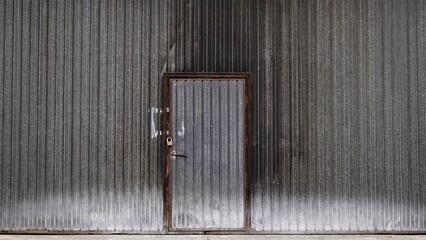 worn dark metal door of industrial factory building