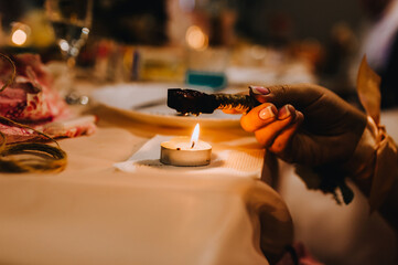 The girl performs the ceremony, the ritual holding melted wax in her hands over a burning candle in...