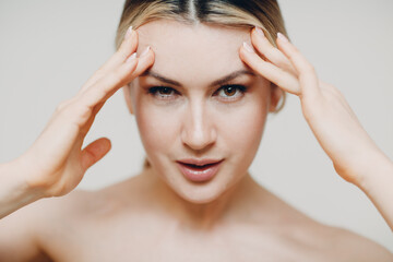 Fototapeta premium Young adult woman doing facial gymnastics self massage and rejuvenating exercises face building and lifting