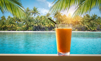 Orange fruity cocktail on beach table of tropical Island.