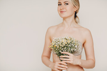Young and beautiful blonde woman with daisies bouquet. Natural eco cosmetics concept