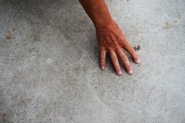 Frauenhand abgestützt auf grauem Betonboden
