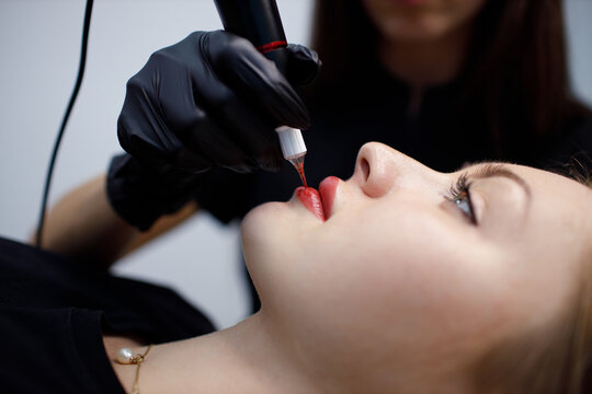 Applying procedure pink pigment permanent tattoo on female lips with tatooing needle machine