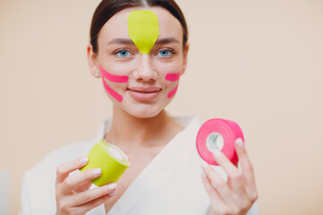 Beautiful woman applying tape lifting treatment procedure on face