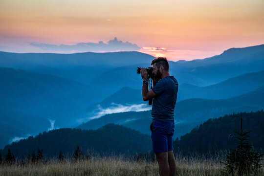 man taking photos of sunset in mountains