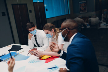 Fototapeta premium Businessman and businesswoman team in medical face mask at office meeting. Business people group conference discussion with boss.