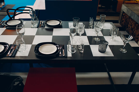 Wedding table decor like a chessboard with black and white dishes glasses.