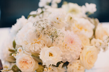 round tables in the restaurant with white tablecloths and white bouquets of flowers decor.