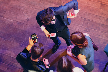 magician shows guests card tricks at the party top view.
