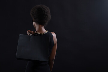 African american woman with afro hairstyle holds black shopping bags. Sale and discounts on market...