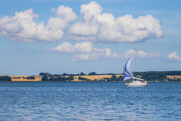 Landscape with the sea and a sailing boat against the backdrop of the island of R&uuml;gen in Germany