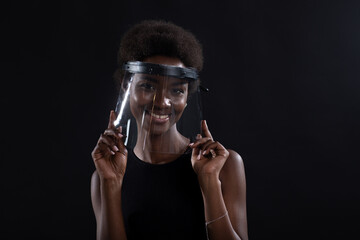 African american woman in transparent protective face mask shield on black background. Safety concept Covid-19 coronavirus protection.