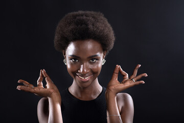 Studio portrait of african american female model showing zen yoga mudra or okay sign gesture. Woman...