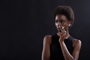 Sexy african american woman smoking cigarette on black background.