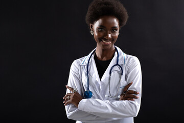 Black female doctor smiling at black background. African american woman in medical gown with...