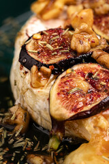  Baked brie with nuts and figs in a green bowl. Close up.