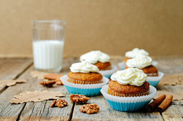 Carrot cupcake with cream cheese frosting on a wood background