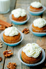 Obraz na płótnie Canvas Carrot cupcake with cream cheese frosting on a wood background