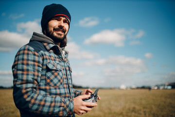 Man pilot controlling quadcopter drone with remote controller pad.