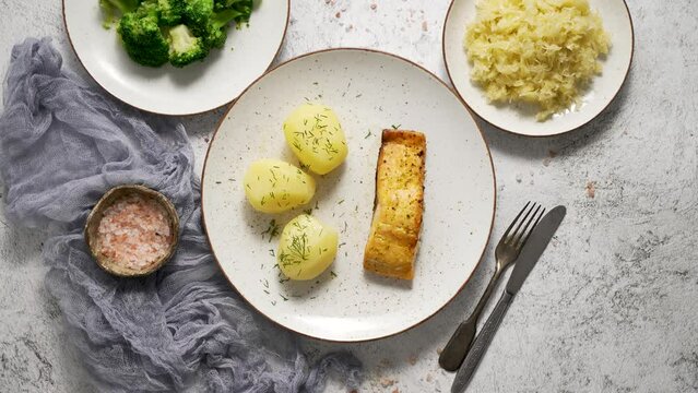 Homemade baked salmon served with popatoes, broccoli and sauerkraut