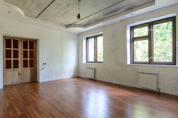 Interior of an empty room during renovation, view of a wall with windows and a wall with a door