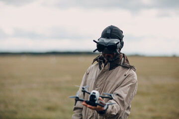 Man controlling fpv quadcopter drone for aerial photography and videography with goggles antenna...