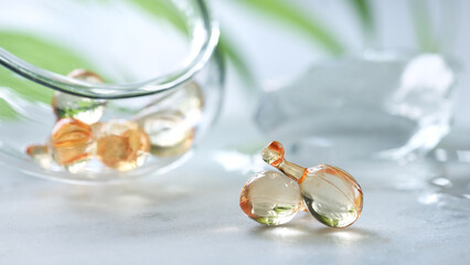 Serum capsules, blurred background with ice. glass jar with the capsules and green leaf.