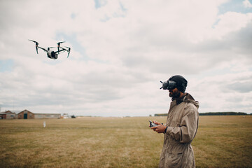 Man controlling fpv quadcopter drone for aerial photography and videography with goggles antenna remote controller.