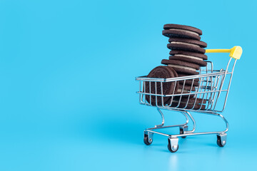Small metal supermarket shopping trolley full of fresh sweet pastries in the form of chocolate...