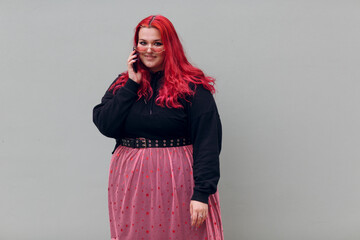 European plus size woman speaking mobile phone. Young red pink haired body positive girl.