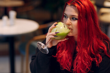 European plus size fat woman drink green smoothie in cafe. Young red pink haired body positive girl...