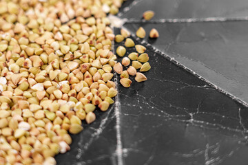 Buckwheat grains on a black grunge paper surface.