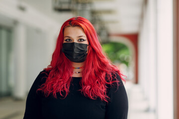 European plus size woman portrait in face mask outdoor street city. Young red pink haired body positive girl.