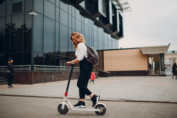 Young woman with electric scooter at the city. © primipil